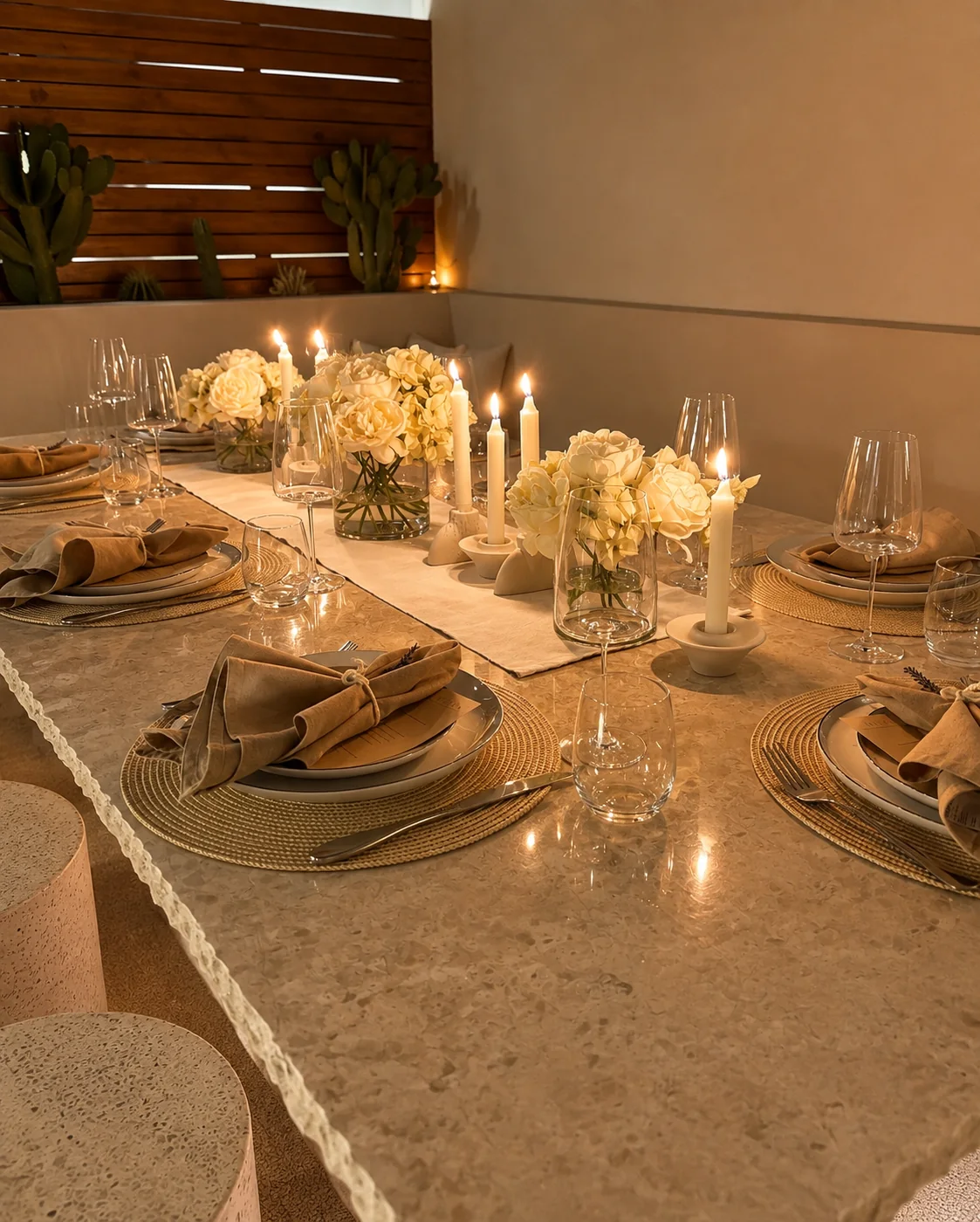 A terrace table dressed for dinner with cream roses, tapered candles and linen napkins